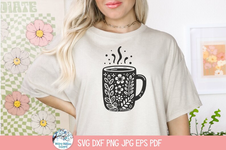 May include: A white t-shirt with a black and white illustration of a coffee mug with floral designs. The mug has steam coming from it and the text "Whispy Willow" is at the bottom of the mug.