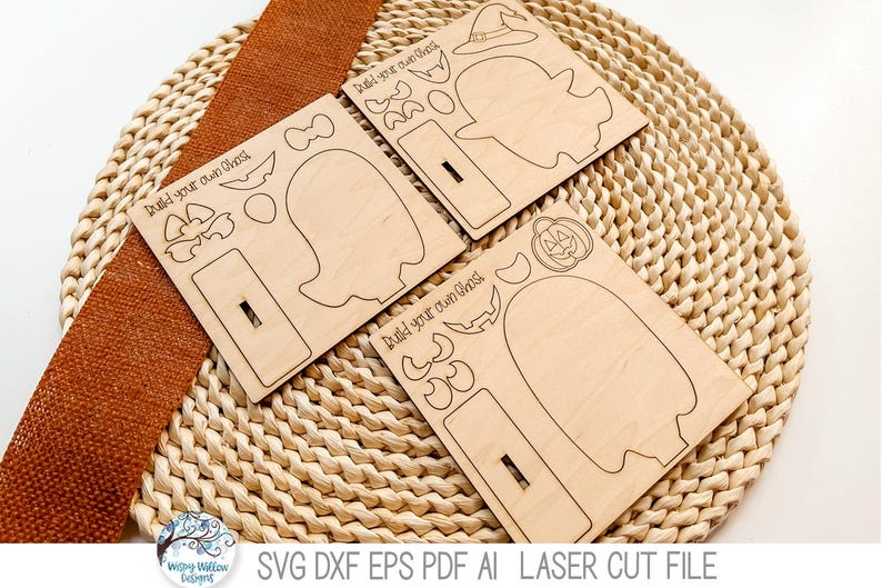 May include: Three light-colored wooden sheets featuring laser-cut outlines for a build your own ghost project. Each sheet includes a ghost shape, a rectangular base with a slot, and various accessories like hats, pumpkins, and facial features.