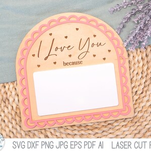 May include: An arched wooden sign with a scalloped pink border, featuring the engraved text "I Love You because" and small heart cutouts. The center contains a blank white rectangular space for writing, designed as a laser cut file.