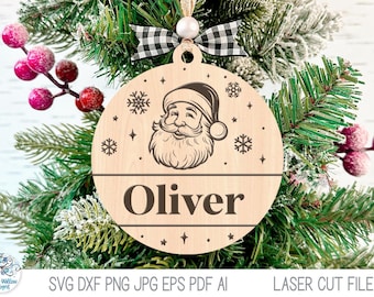 May include: A round light-colored wooden Christmas ornament featuring a laser-engraved illustration of Santa Claus, snowflakes, and the name Oliver in dark brown text. The ornament is topped with a white bead and a black and white buffalo plaid bow.
