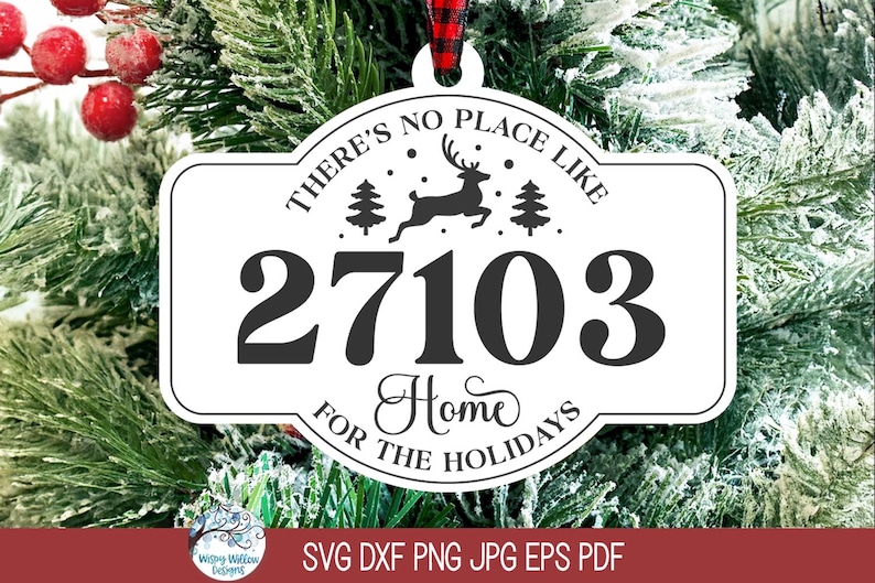 May include: A white, rectangular, rounded-edge Christmas ornament featuring the black text 'THERE'S NO PLACE LIKE 27103 HOME FOR THE HOLIDAYS' with a central graphic of a leaping reindeer between two pine trees, suspended by a red and black plaid ribbon.