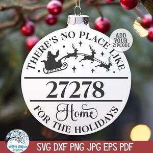 May include: White round Christmas ornament with black text that reads "There's no place like 27278 Home for the Holidays". The ornament features a silhouette of Santa Claus in his sleigh with reindeer flying through the air.