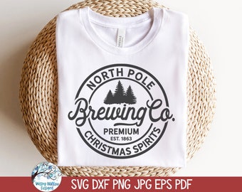 May include: A white t-shirt featuring a black circular graphic with a pine tree silhouette and the text North Pole Brewing Co. Premium Christmas Spirits Est. 1863. The design is centered on the chest of the shirt, which has a crew neckline.
