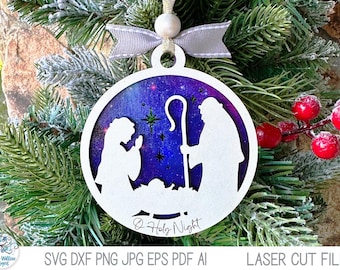 May include: A circular white laser-cut ornament featuring a nativity scene silhouette with Mary, Joseph, and the infant Jesus. The background is a deep purple and blue starry night sky. The text O Holy Night is printed at the bottom.