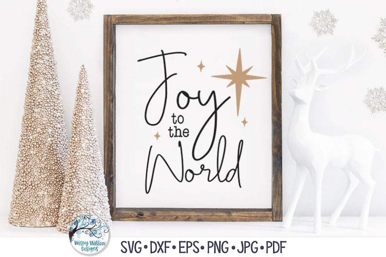 May include: A framed sign with a white background and a dark brown wooden frame. The text reads Joy to the World in black cursive lettering. There are three gold-colored starburst icons of varying sizes positioned near the text.
