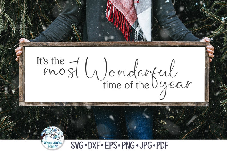 May include: A rectangular wooden sign with a dark brown frame and a white background featuring the black text It's the most Wonderful time of the year. The sign is held horizontally and includes a circular logo with the text Wispy Willow Designs.
