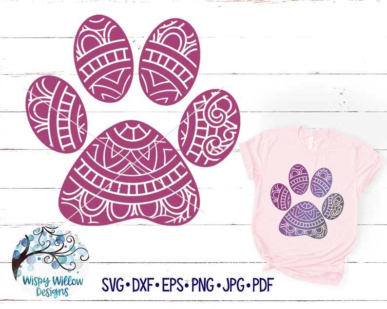 May include: A purple paw print with a mandala design. The paw print is on a white wooden background. The image also includes a pink t-shirt with the same paw print design in a gradient of purple and blue.