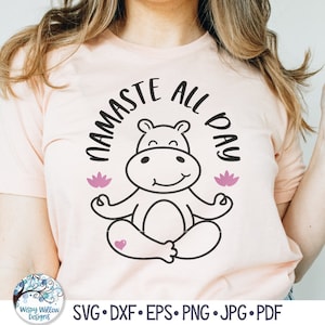 May include: A pink t-shirt with the text "Namaste All Day" in black lettering. A cartoon hippopotamus is meditating in a yoga pose with pink lotus flowers on either side.