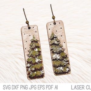 May include: A pair of wooden earrings with a wintery design. Each earring features a white background with a green pine tree and white snowflakes.