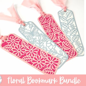 May include: A set of four rectangular bookmarks featuring intricate laser-cut floral and butterfly patterns. Two bookmarks are in vibrant pink and two are in light blue. Each bookmark has a hole at the top with a tied light pink fabric ribbon.