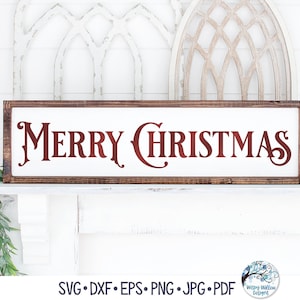Op de afbeelding: Een houten bord met een witte achtergrond en een bruine lijst. Het bord zegt "Merry Christmas" in rode cursieve letters.