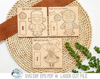 May include: Three square light-colored wooden panels featuring laser-cut designs for building a Frankenstein monster, a mummy, and a witch. Each panel includes character parts, a pumpkin, and a base stand, with text labels Build your own Frankenstein, Build your own Mummy, and Build your own Witch.