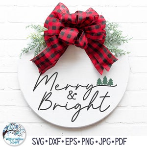 May include: A round white wooden sign featuring the black text Merry & Bright with three small green pine trees. A large red and black buffalo plaid ribbon bow is attached to the top, accented with green pine sprigs and small white berries.