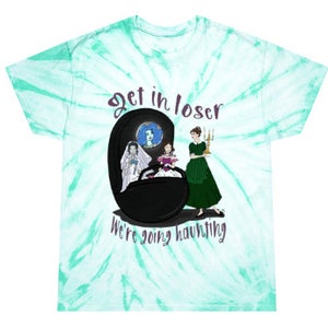 May include: A tie-dye t-shirt with a teal and white swirl pattern. The shirt features a graphic of three women and the text "Get in loser, we're going haunting" in purple and white.