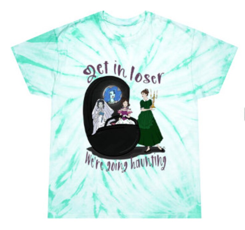 May include: A tie-dye t-shirt with a teal and white swirl pattern. The shirt features a graphic of three women and the text "Get in loser, we're going haunting" in purple and white.