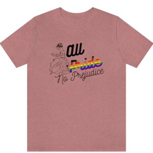 K&ouml;nnte beinhalten: Ein pinkfarbenes T-Shirt mit einer Regenbogengrafik, auf der "all pride no prejudice" steht.
