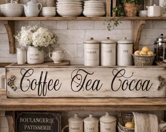 May include: A rustic kitchen scene with a wooden sign reading "Coffee Tea Cocoa." The sign is above a shelf with canisters labeled "Farine," "Cafe," and "The." Other shelves display dishes, a teapot, and a vase of white flowers.