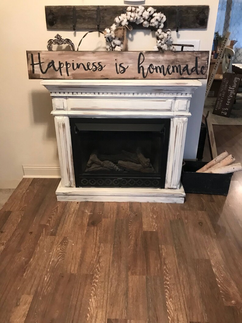 May include: A white painted fireplace mantel with a wooden sign above it that reads "Happiness is homemade".