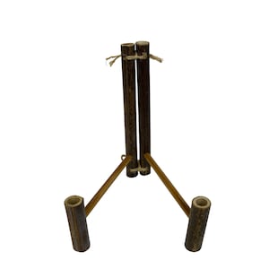 May include: A wooden stand with three legs and a vertical support made of two pieces of bamboo tied together with twine. The stand is designed to hold items like plants or other decorative objects.