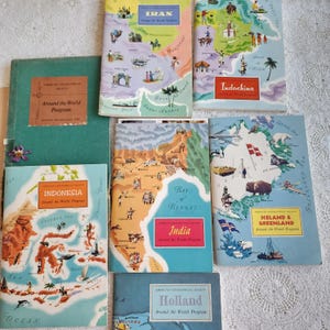May include: A collection of seven vintage American Geographical Society Around the World Program booklets featuring illustrated maps of Iran, Indochina, Indonesia, India, Iceland, Greenland, and Holland, with colorful regional graphics and text.