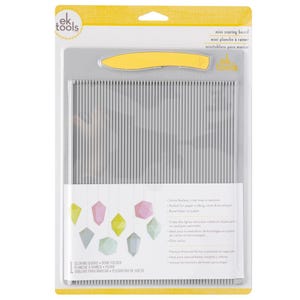 Puede incluir: Una mini tabla de puntuación con una superficie gris y ranuras verticales, empaquetada con un plegador de hueso amarillo. El paquete incluye texto en inglés, francés y español y presenta formas geométricas coloridas.