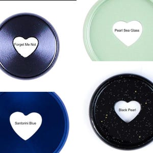 May include: Four circular plastic discs with a heart-shaped cutout in the center. The discs are labeled Forget Me Not in dark blue, Pearl Sea Glass in light green, Santorini Blue in royal blue, and Black Pearl with gold flecks.