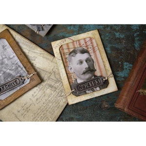 Peut inclure: Composition de papiers anciens, dont un portrait d'homme &agrave; moustache, une photo et des documents manuscrits. Le portrait porte une &eacute;tiquette m&eacute;tallique avec le num&eacute;ro "No. 4103". Le mot "ARCHIVE" est sur une &eacute;tiquette m&eacute;tallique. Sur une surface bleue vieillie.