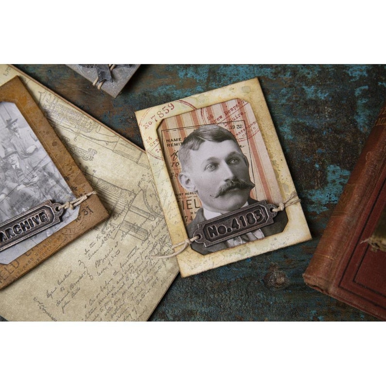 Peut inclure: Composition de papiers anciens, dont un portrait d'homme &agrave; moustache, une photo et des documents manuscrits. Le portrait porte une &eacute;tiquette m&eacute;tallique avec le num&eacute;ro "No. 4103". Le mot "ARCHIVE" est sur une &eacute;tiquette m&eacute;tallique. Sur une surface bleue vieillie.
