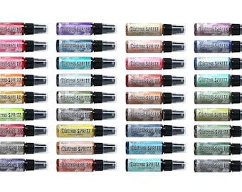 Puede incluir: Una colección de botellas de spray Distress Spritz en varios colores. Cada botella tiene una tapa negra y una boquilla transparente. Las botellas están etiquetadas con el nombre del producto en texto blanco.