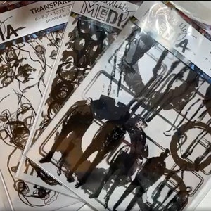 May include: Three packages of Dina Wakley Media transparencies. Each package contains 6 clear sheets printed with black ink. The sheets are 8.5 inches by 10.75 inches.