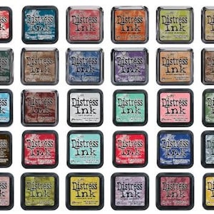 Könnte beinhalten: Eine Sammlung von 24 Distress Ink Pads in verschiedenen Farben. Jedes Pad ist mit dem Text "Distress Ink" und dem Farbnamen beschriftet. Die Ink Pads sind in einem Raster von vier Reihen und sechs Spalten angeordnet.