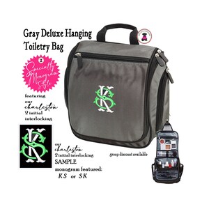 May include: Gray hanging toiletry bag with a black zipper and a green monogram of the letters KS. The bag has a hook for hanging and a small pocket on the side. The text "Specialty Monogram Style" is on a pink circle. The text "featuring our charleston 2 initial interlocking" is below the circle. The text "our charleston 2 initial interlocking SAMPLE monogram featured: KS or SK" is below the bag. The text "group discount available" is on the right side of the bag.