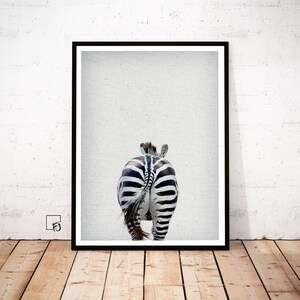 May include: A black and white zebra with its tail visible, walking away from the camera. The zebra is in focus against a light gray background.
