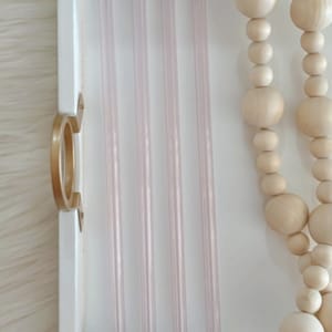 Pu&ograve; includere: Cinque cannucce da bere in vetro trasparente con una leggera sfumatura rosa chiaro sono disposte in fila su un vassoio bianco. Le cannucce sono tutte della stessa lunghezza e larghezza. Il vassoio &egrave; in legno e ha una maniglia dorata.