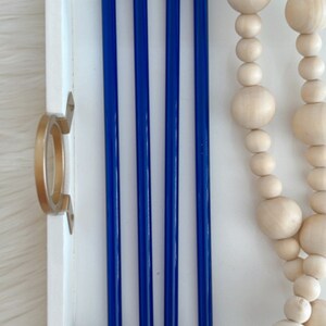 Pu&ograve; includere: Cinque cannucce da bere in vetro blu in un vassoio bianco. Le cannucce sono disposte in fila, con le estremit&agrave; delle cannucce allineate. Le cannucce sono lunghe circa 25 cm.