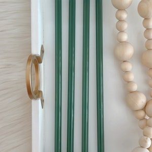 Pu&ograve; includere: Cinque cannucce da bere in vetro verde scuro in un vassoio bianco. Le cannucce sono disposte in fila, con le estremit&agrave; delle cannucce allineate.