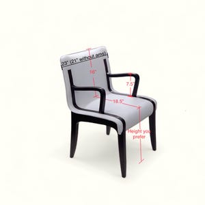 May include: A white upholstered chair with black trim and wooden legs. The chair has a 23 inch back height, 16 inch seat width, 7.5 inch arm length, and 18.5 inch seat depth.