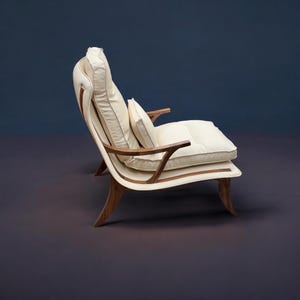 May include: A white leather armchair with a curved wooden frame and a pillow. The chair is on a dark grey background.
