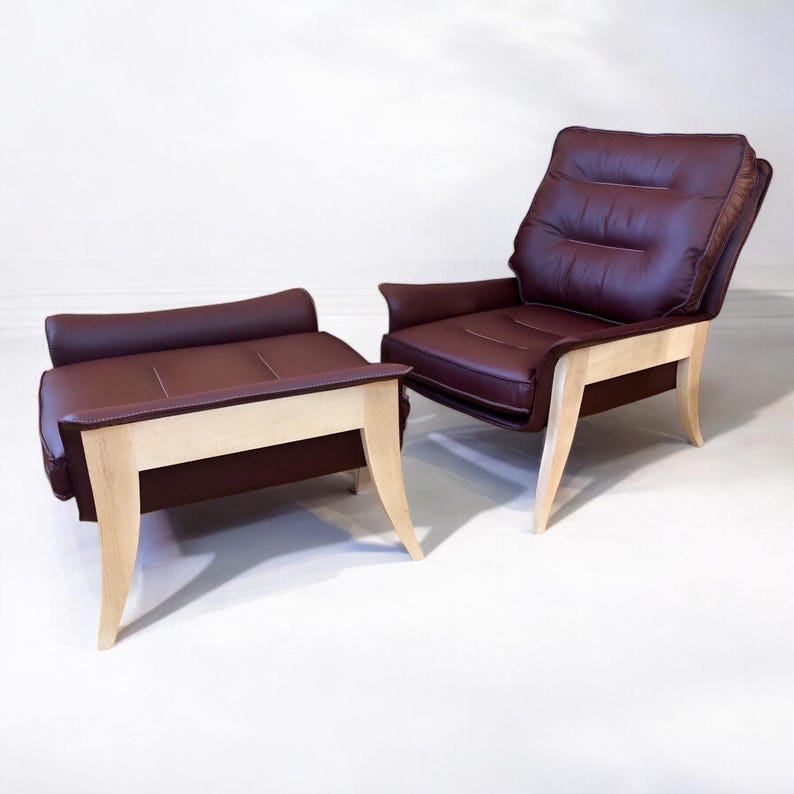 May include: A brown leather armchair with a matching ottoman. Both pieces have light wood legs and a tufted back.