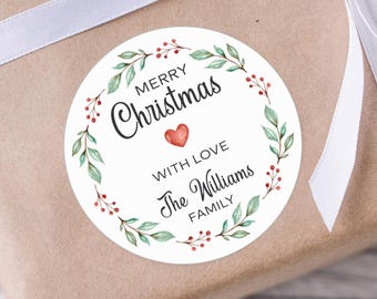 May include: A round Christmas gift sticker with the text "MERRY Christmas" and "WITH LOVE The Williams FAMILY" in a wreath design. The sticker is on a wrapped gift with a white ribbon.