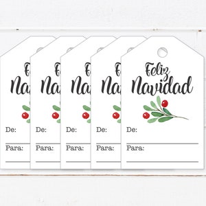 May include: Five white gift tags with a green sprig and red berries. The text "Feliz Navidad" is written on the tag on the right. The other tags have the text "Na" visible. Each tag has the words "De:" and "Para:" written below the main text.
