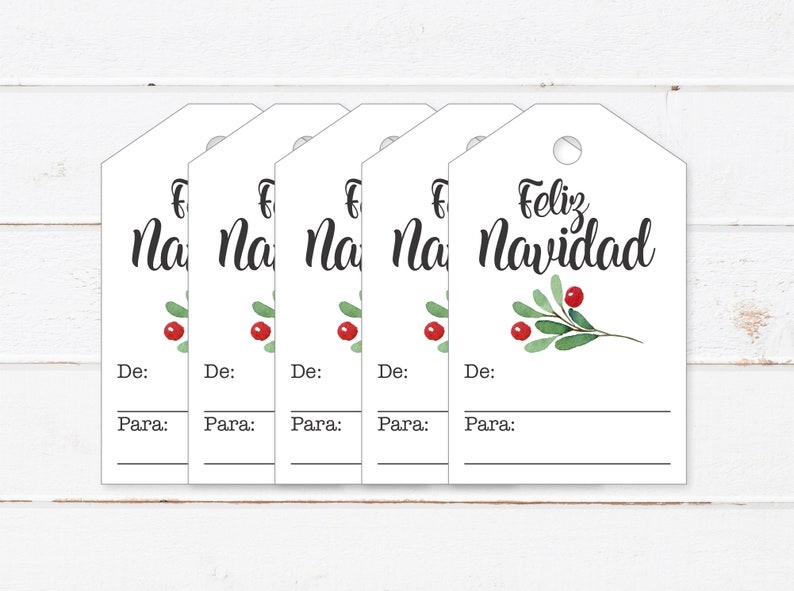 May include: Five white gift tags with a green sprig and red berries. The text "Feliz Navidad" is written on the tag on the right. The other tags have the text "Na" visible. Each tag has the words "De:" and "Para:" written below the main text.