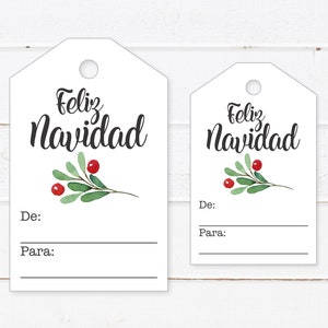 May include: Two white gift tags with a green holly sprig and red berries. The larger tag says "Feliz Navidad" and the smaller tag says "Feliz Navidad". Both tags have blank lines for "De:" (From) and "Para:" (To).