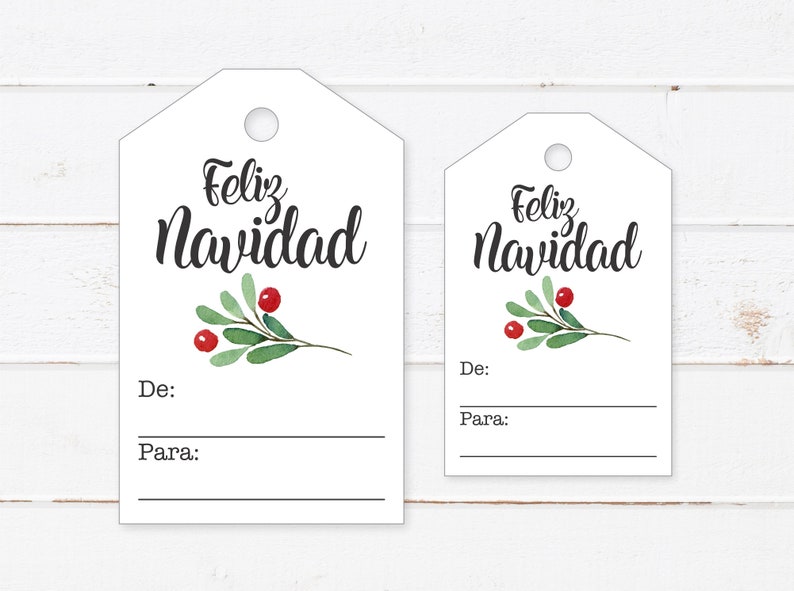 May include: Two white gift tags with a green holly sprig and red berries. The larger tag says "Feliz Navidad" and the smaller tag says "Feliz Navidad". Both tags have blank lines for "De:" (From) and "Para:" (To).