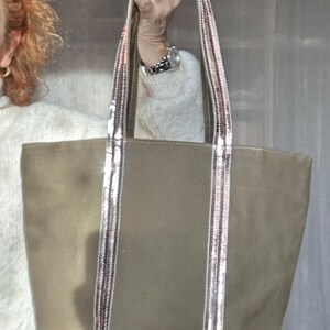 May include: A large, olive green canvas tote bag with pink and silver sequined straps and trim.