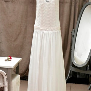 May include: A white lace wedding dress with a flowing skirt and a lace bodice.