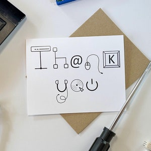 May include: A white card with the text "Thank you" written in black ink. The text is surrounded by small drawings of computer-related items, such as a keyboard, mouse, and monitor. The card is sitting on a brown envelope. There is a screwdriver, a keyboard, a network cable, and a small circuit board in the background.