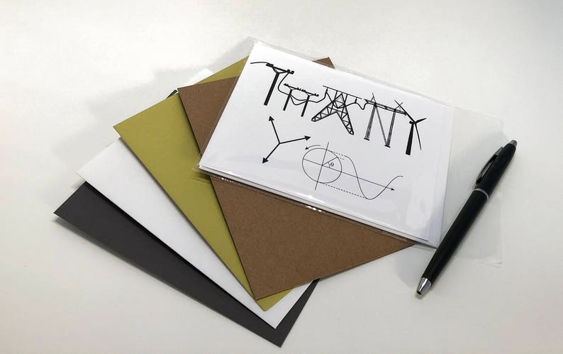 May include: A white card with the word "THANK" spelled out using illustrations of electrical towers and wind turbines. The card is on top of a stack of brown, beige, and gray paper. A black pen is lying on the table next to the card.
