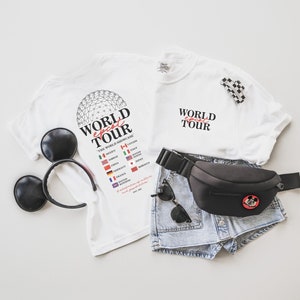 May include: Two white t-shirts with the text "World Ghost Tour" and a list of countries. One shirt has a graphic of the Epcot Spaceship Earth. A black fanny pack with a Mickey Mouse graphic, a pair of denim shorts, and a pair of black Mickey Mouse ears.