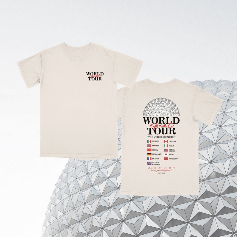 May include: A beige t-shirt with a graphic of the Epcot World Showcase on the back. The graphic includes the Epcot logo, the text "World Epcot Tour", and flags representing the countries in the World Showcase. The front of the shirt has the text "World Tour" in black.
